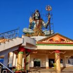 Shiva statue in Pumdikot, reflecting the Shiva temples in Nepal, with a clear blue sky and mountains.